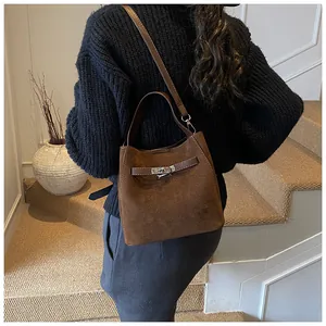 Détail du sac seau en daim marron foncé avec fermoir métallique et bandoulières