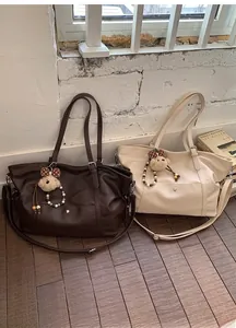 Detail of vintage large tote bags in brown and beige with plush bear charms