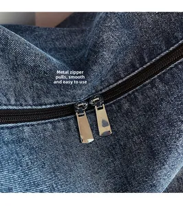 Detail of silver metal zipper pull and denim texture on large capacity tote bag