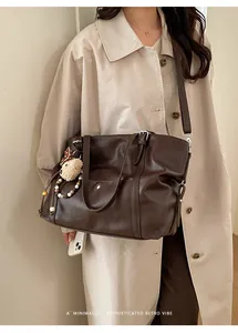 Detail of dark brown retro tote bag with plush bear charm and beaded strap on trench coat