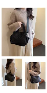 Détail du sac seau en nylon noir imperméable avec large bandoulière tissée et logo