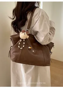 Detail of vintage brown leather tote bag with cute bear charm worn by a model