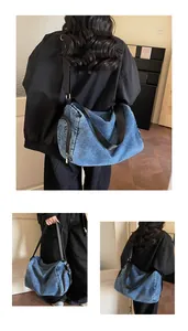 Close-up of washed blue denim tote bag showing side zipper pocket and black strap detail