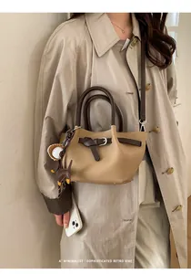 Detail der khakifarbenen Leder-Beuteltasche mit Hunde-Charm und braunem Gurt