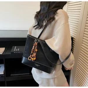 Detail of black leather tote bag with wood bead tassel and gold embossed lettering