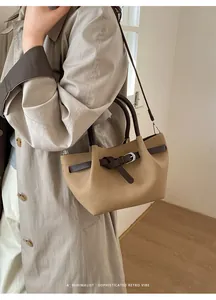 Detail der minimalistischen beigen Beuteltasche mit braunem Griff und silberner Schnalle