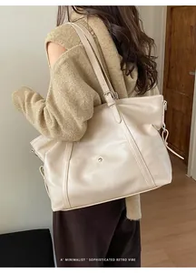 Detailed view of cream PU leather tote bag with adjustable straps and metal snap buckle