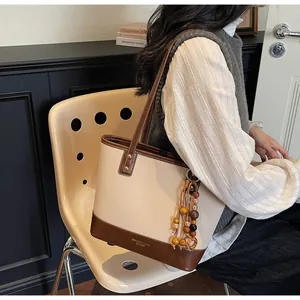 Detail of vintage beige and brown patchwork tote bag with wooden bead tassel and logo