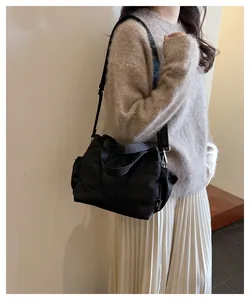 Détail du sac seau en nylon noir avec étiquette logo blanche et large bandoulière