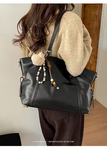 Detail of retro large capacity black tote bag with plush charm on casual shoulder strap