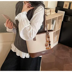 Detail of canvas tote bag with brown leather trim and retro wooden bead pendant