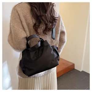 Détail du sac seau noir en nylon avec sa bandoulière en textile logotypée