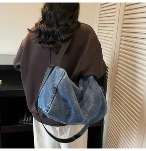 Detail showing high-capacity blue denim crescent bag with wide black shoulder strap