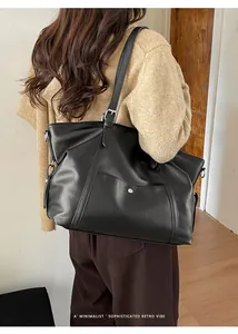 Minimalist black retro tote bag worn by a model showing large capacity and sleek leather