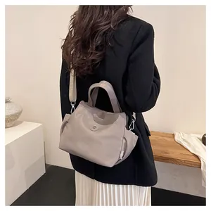 Détail du sac seau en nylon gris-violet avec large bandoulière imprimée et poches latérales