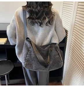 Detail of grey washed denim hobo bag featuring a wide nylon shoulder strap and large capacity