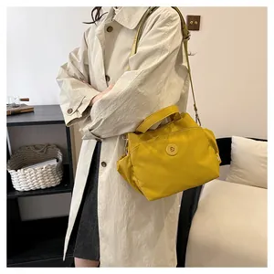 Détail d'un sac seau en nylon jaune vif porté avec un trench-coat beige élégant