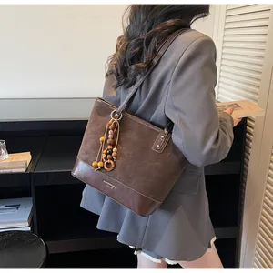 Detail of brown suede tote bag with wooden bead charm and smooth leather trim