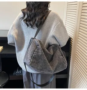 Detail view of large dark grey denim tote bag with black wide shoulder strap on model