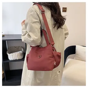 Détail du sac seau en nylon bordeaux avec bandoulière réglable porté en travers