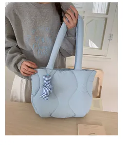 Detail of light blue quilted tote bag featuring a blue and white checkered bow charm