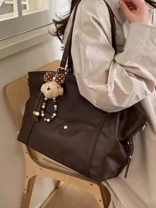 Large vintage brown faux leather tote bag with plush bear charm worn by a model