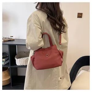 Gros plan du sac seau en nylon rouge brique avec logo et bandoulière stylée à lettres