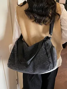 Large gray denim tote bag with wide nylon strap and side zipper pocket shown on model