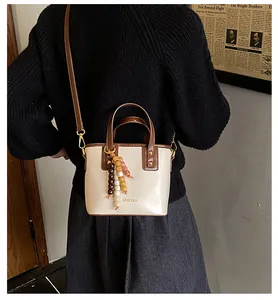 Détail du sac seau beige avec poignée contrastée et charm de perles colorées élégant