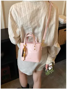 Détail du sac seau en cuir rose avec pendentif en perles de bois et bandoulière réglable