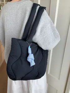 Minimalist black quilted puffer tote bag with a blue checkered pendant for daily commuting