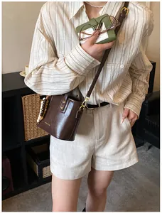 Détail d'un sac seau en cuir marron avec perles et logo Cherie doré sur le devant