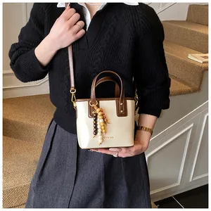 Détail du sac seau crème avec poignées marron foncé et perles en bois colorées