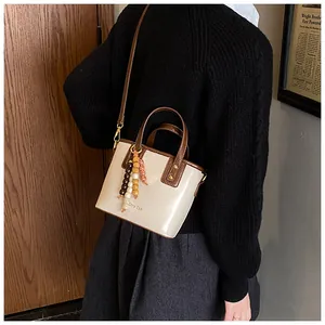 Détail du sac seau vintage en cuir verni crème avec pendentif décoratif en perles