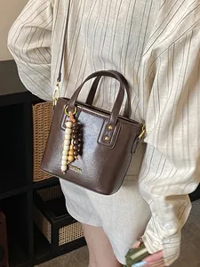 Sac seau rétro marron foncé avec perles en bois et poignée porté par un mannequin