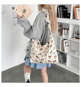 Detail of pleated shoulder strap on a beige tote bag with colorful pony prints