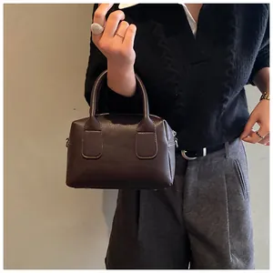 Gros plan sur la texture du cuir litchi marron et les poignées d'un sac à main chic