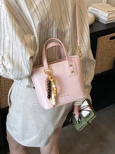 Sac seau rose en cuir PU avec breloque en bois porté par un mannequin dans une bibliothèque