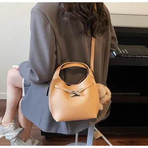 Detail view of a light brown lychee leather bucket bag with silver lock and plush charm