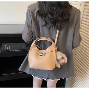 Detail view of a beige pebble leather bucket bag with silver buckle and cute rabbit charm