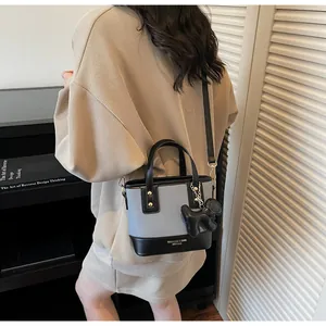 Detail of color-block bucket bag in blue canvas and black leather with dog charm