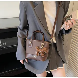 Detailed shot of brown bucket bag with puppy charm and branding on a shoulder strap