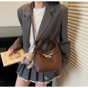 Detail of dark brown pebble leather bucket bag with silver cross lock and plush bunny charm