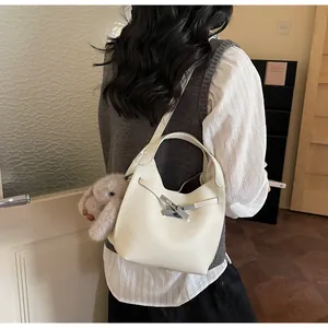Detail of cream pebbled leather bucket bag with bamboo clasp and plush rabbit charm