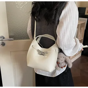 Detail of white lychee leather bucket bag with silver metal twist lock and rabbit charm