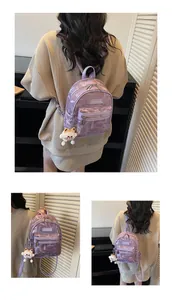 Detail des lila Kunstleder-Rucksacks mit Buchstabendruck und weißem Katzen-Anhänger