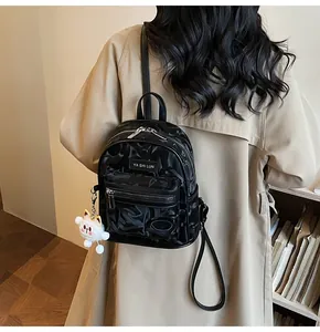 Detail eines schwarzen Mini-Rucksacks mit Blumenprägung und weichem Katzenanhänger