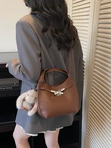Brown lychee leather bucket bag with silver clasp and plush bunny charm on a model