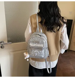 Silberner Mini-Rucksack mit geometrischen Mustern und Bärenanhänger an einem Model