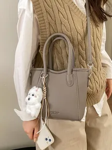Sac seau gris en cuir grainé avec breloque chiot et bandoulière porté par un mannequin
